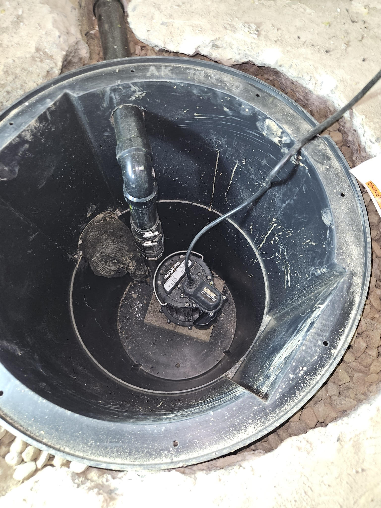 Installed sump pit with sump pump set inside and discharge piping connected